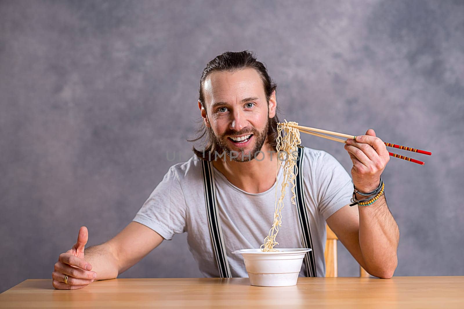 young man eating asian food and smiling in to the camera