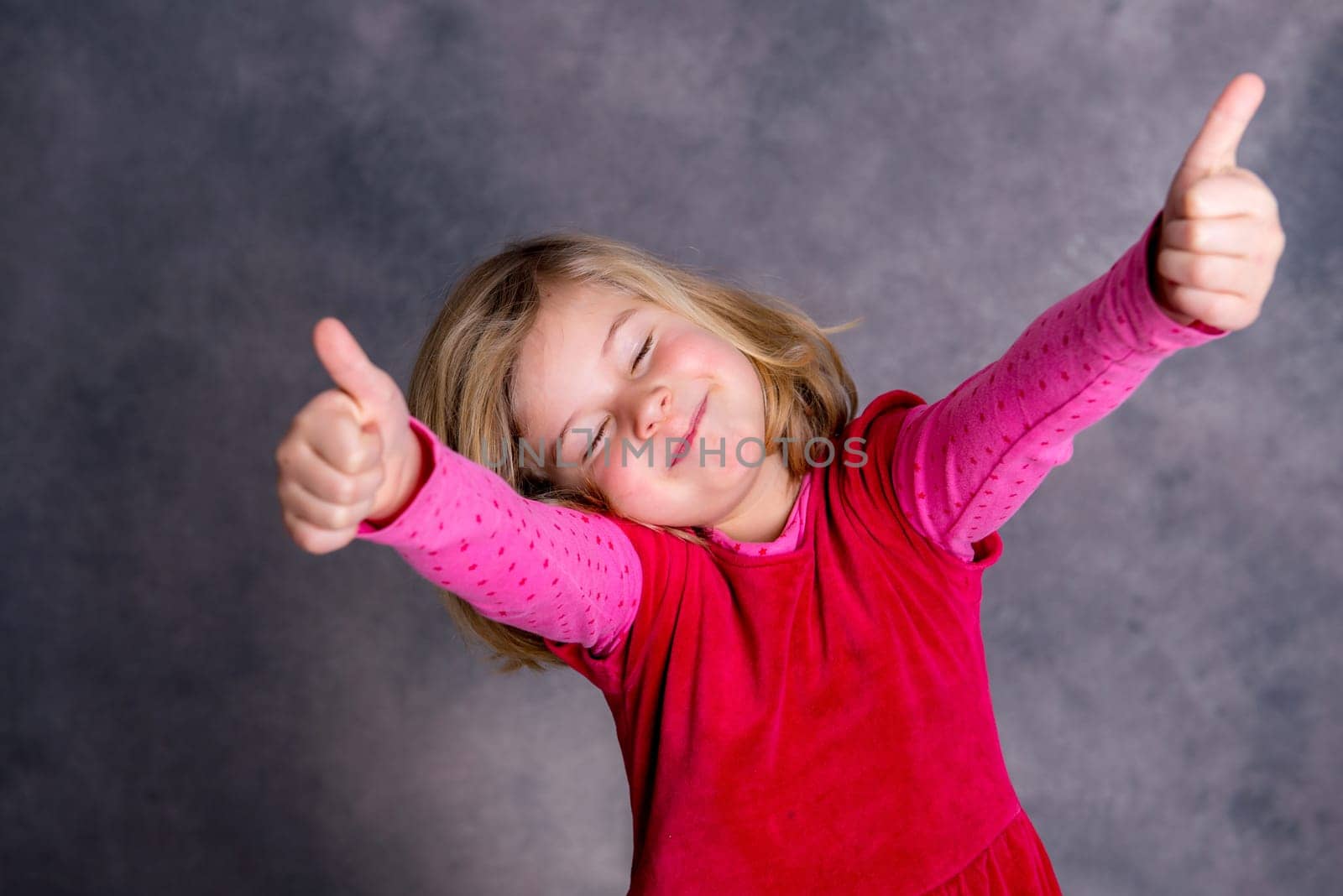 funny girl with thumbs up in front of gray background