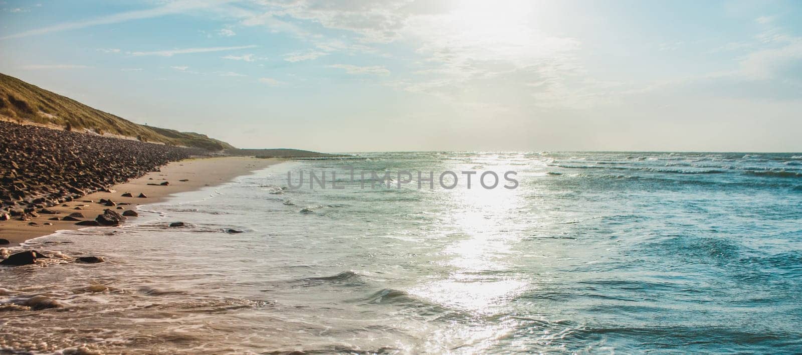 An endless sandy beach and a lonely surfer in the blue sea