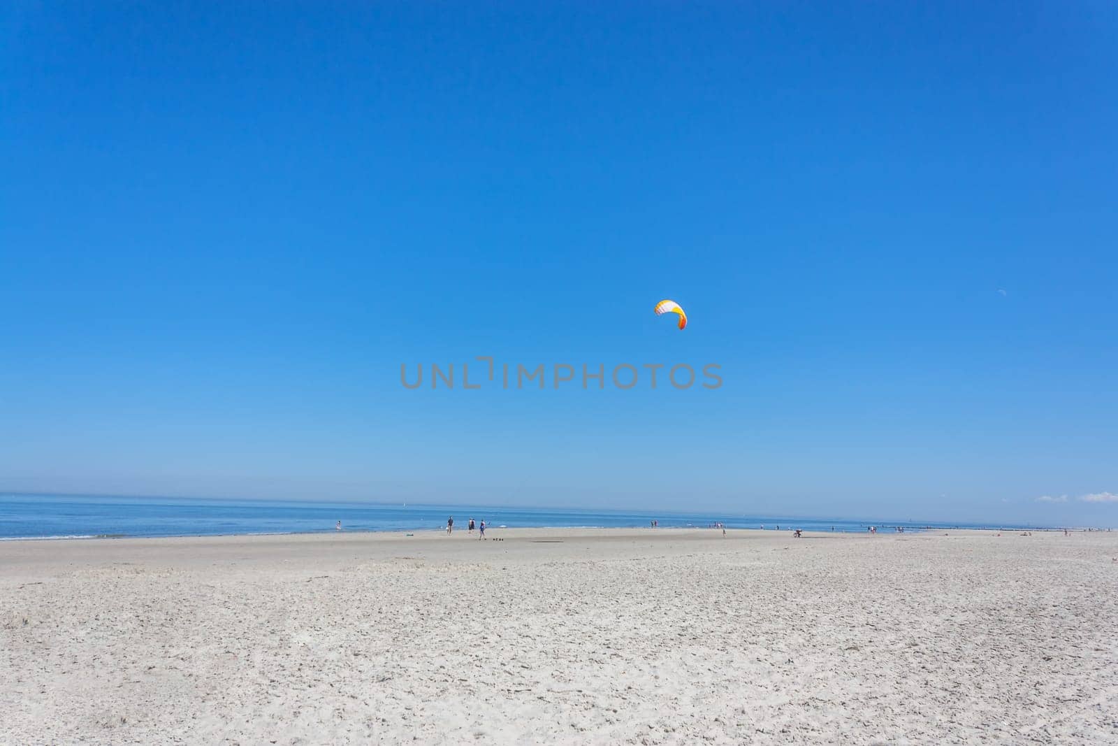 An endless sandy beach and a lonely surfer in the blue sea