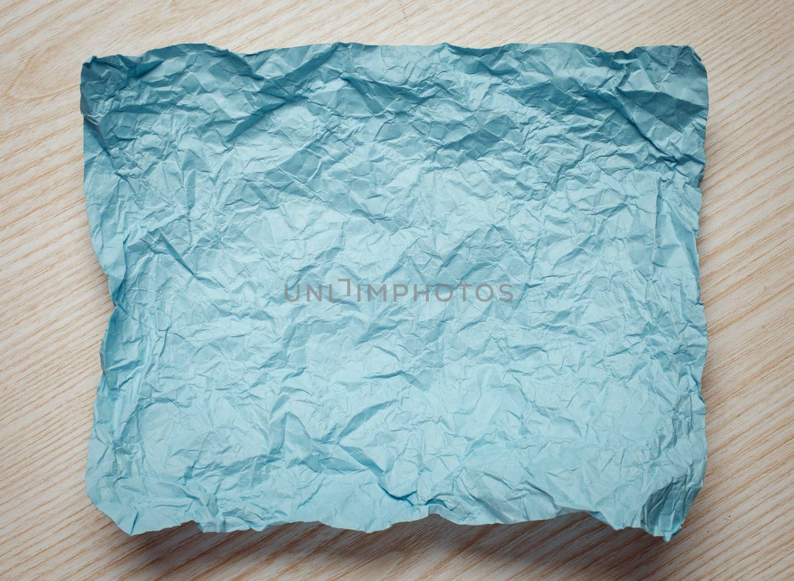 Crumpled  cyan paper card on beige background, place for tex