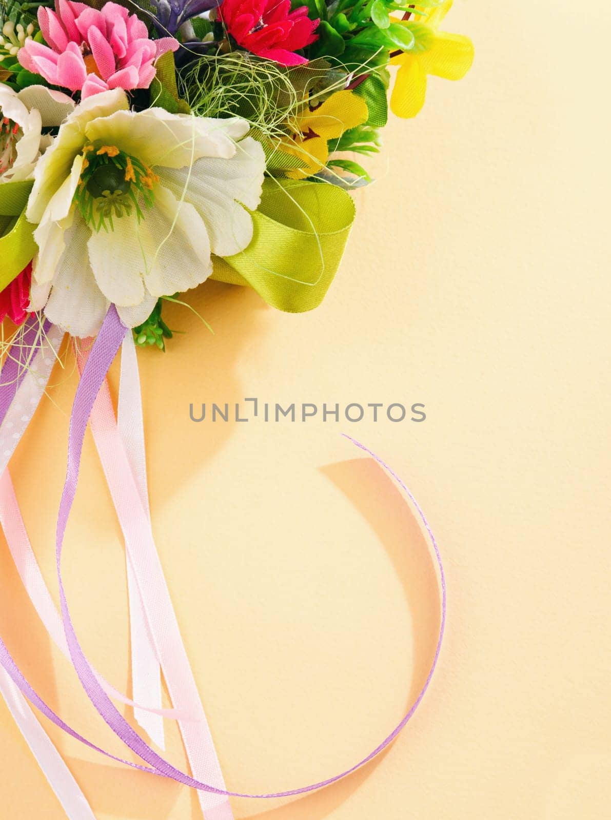 artificial flowers and streamers on cream background with place for label relamy