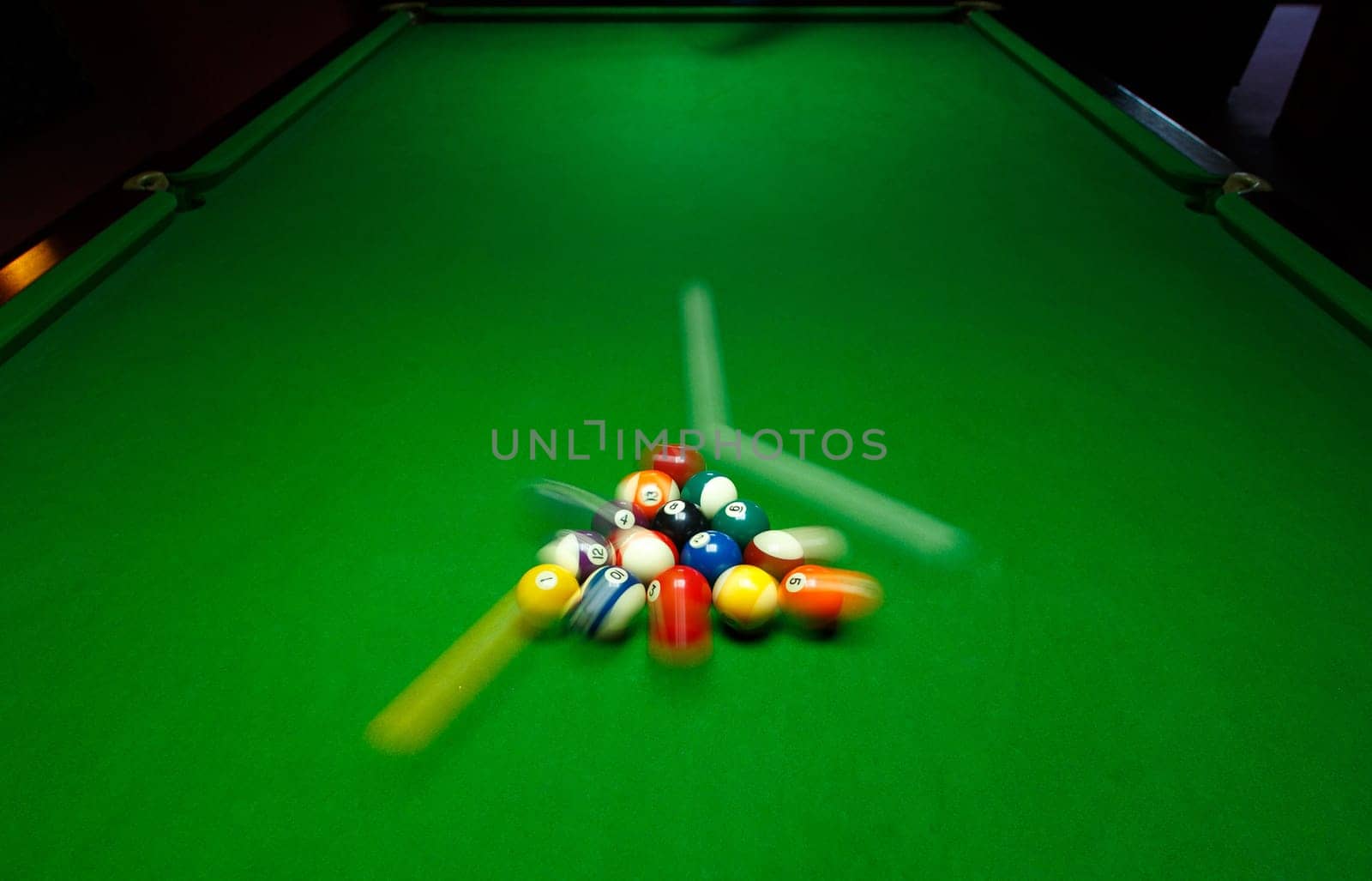 green billiard table with colorful balls, beginning of game, slow motion, soft focus, snooker bar, entertainment in nightclub, hobby and sport concept