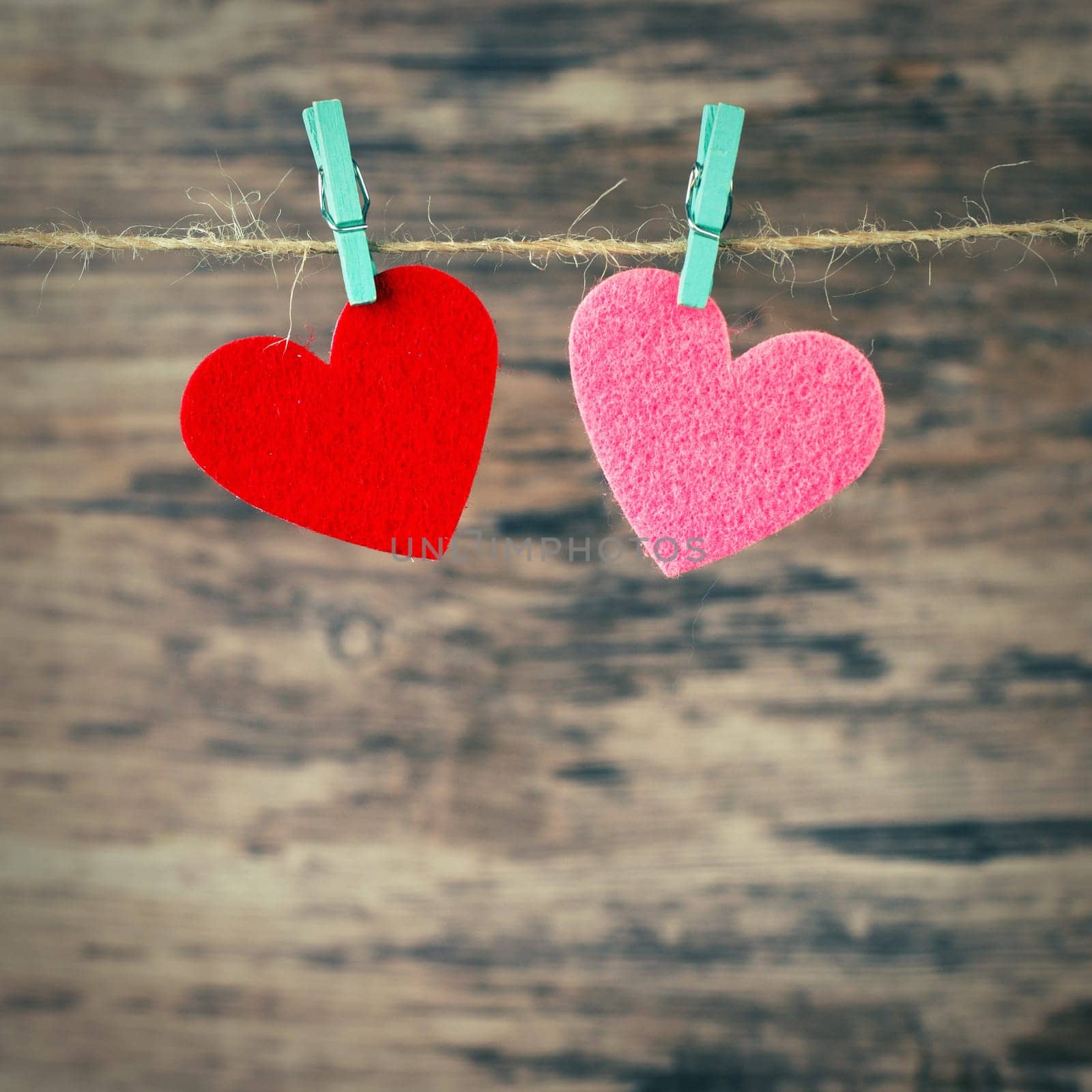 two  hearts hanging on a cord on a wooden background, love background