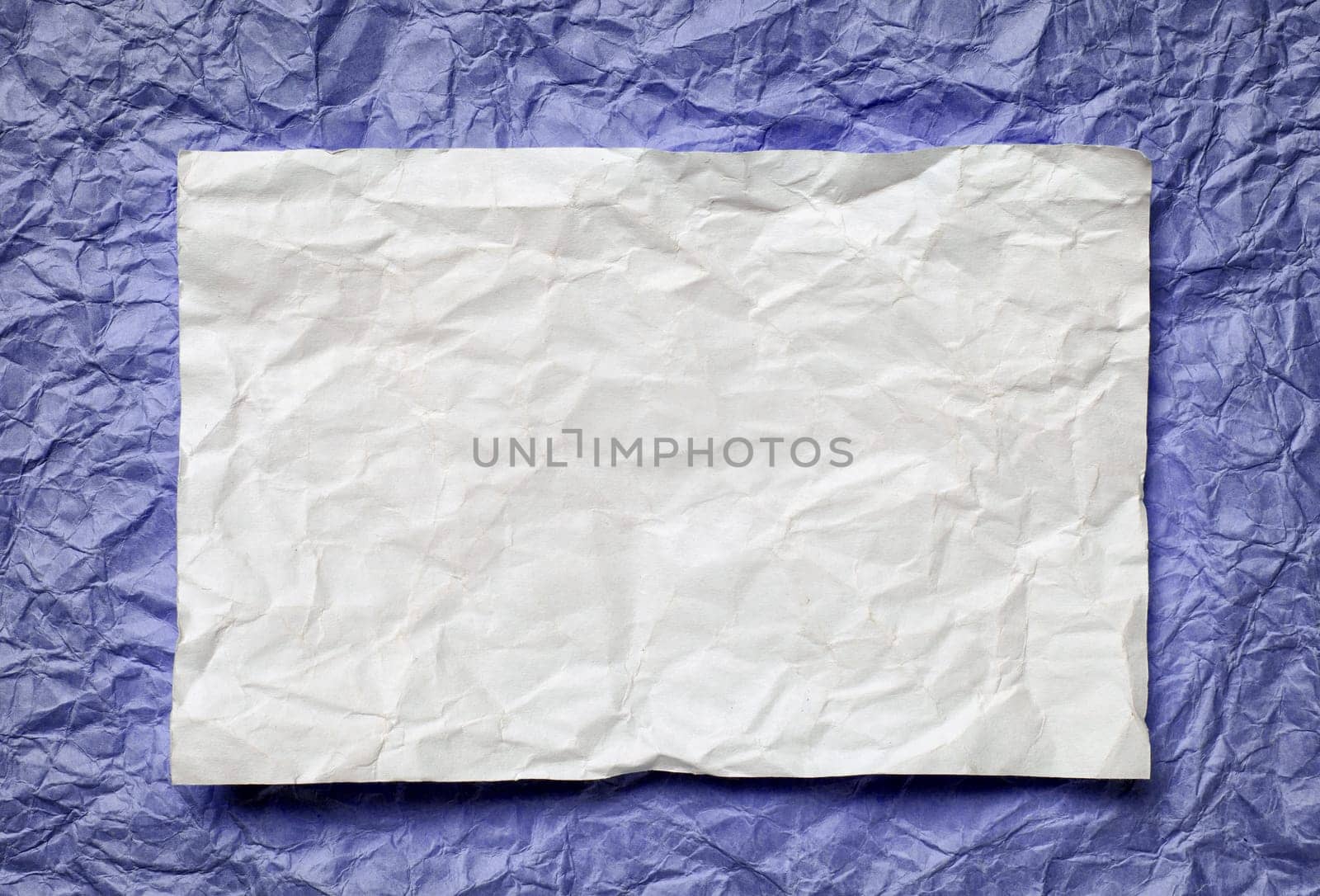 Crumpled  white paper card on violet  background, place for tex