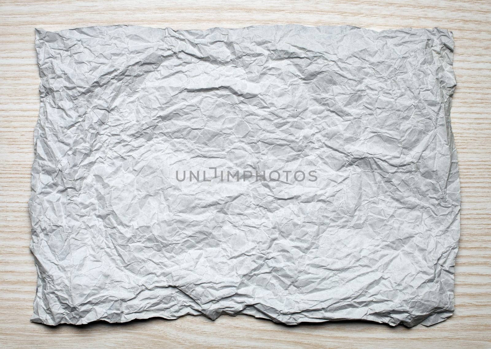 Crumpled  white paper card on wooden background, place for tex