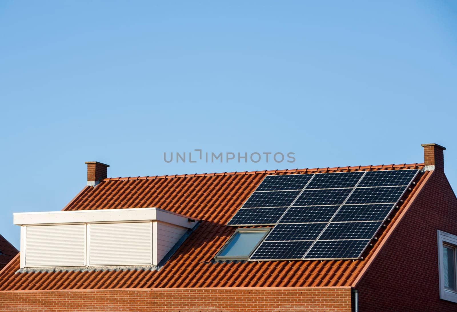 Roof with solar panels and skylight protected with a rolling shutter