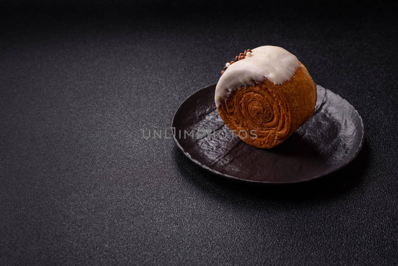Round sweet New York roll croissant with pistachio cream filling on a dark concrete background