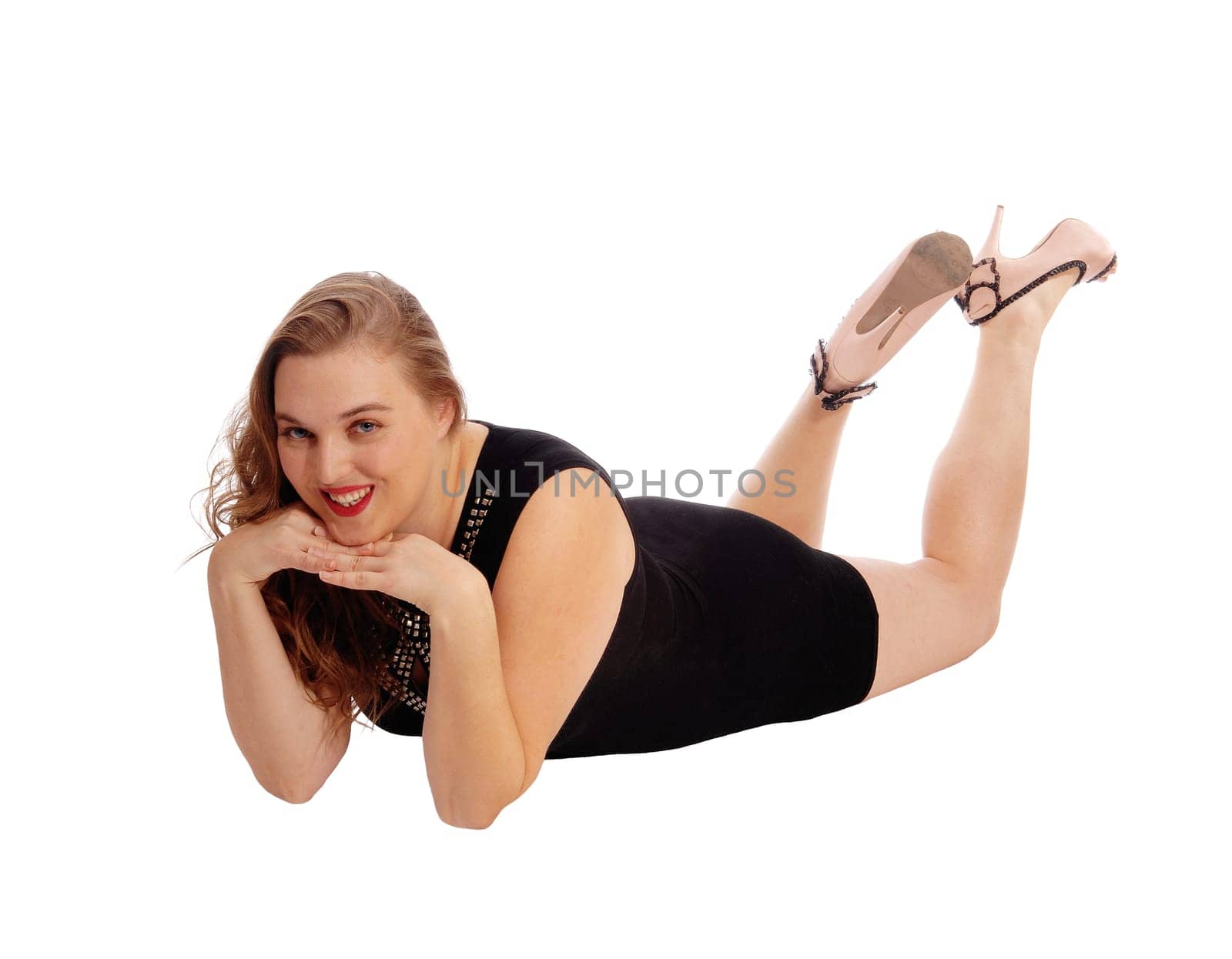 A pretty woman in a black dress lying on the floor with her hands under.her chin, isolated for white background..