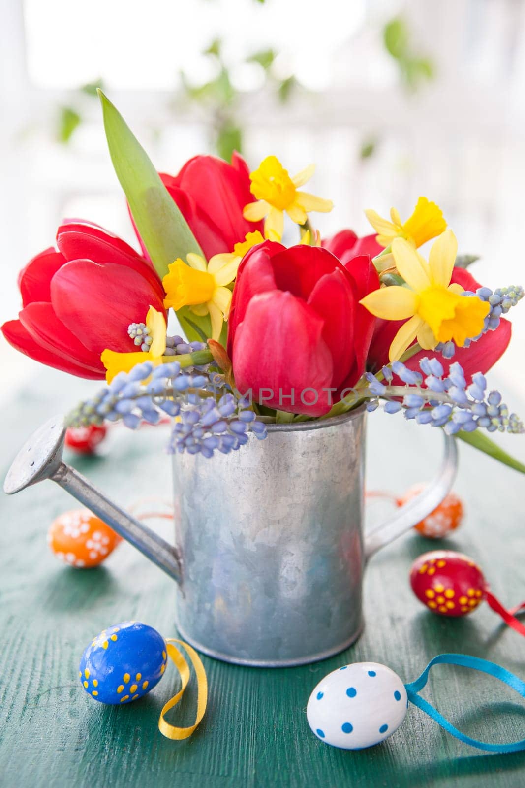 Fresh colorful spring flowers and small Easter eggs