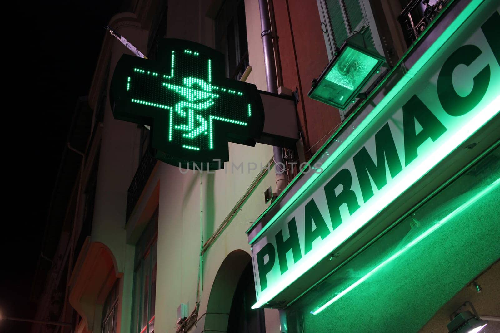 French Pharmacy Neon Green Sign by Night. Bowl of Hygieia is one of the symbols of Pharmacy