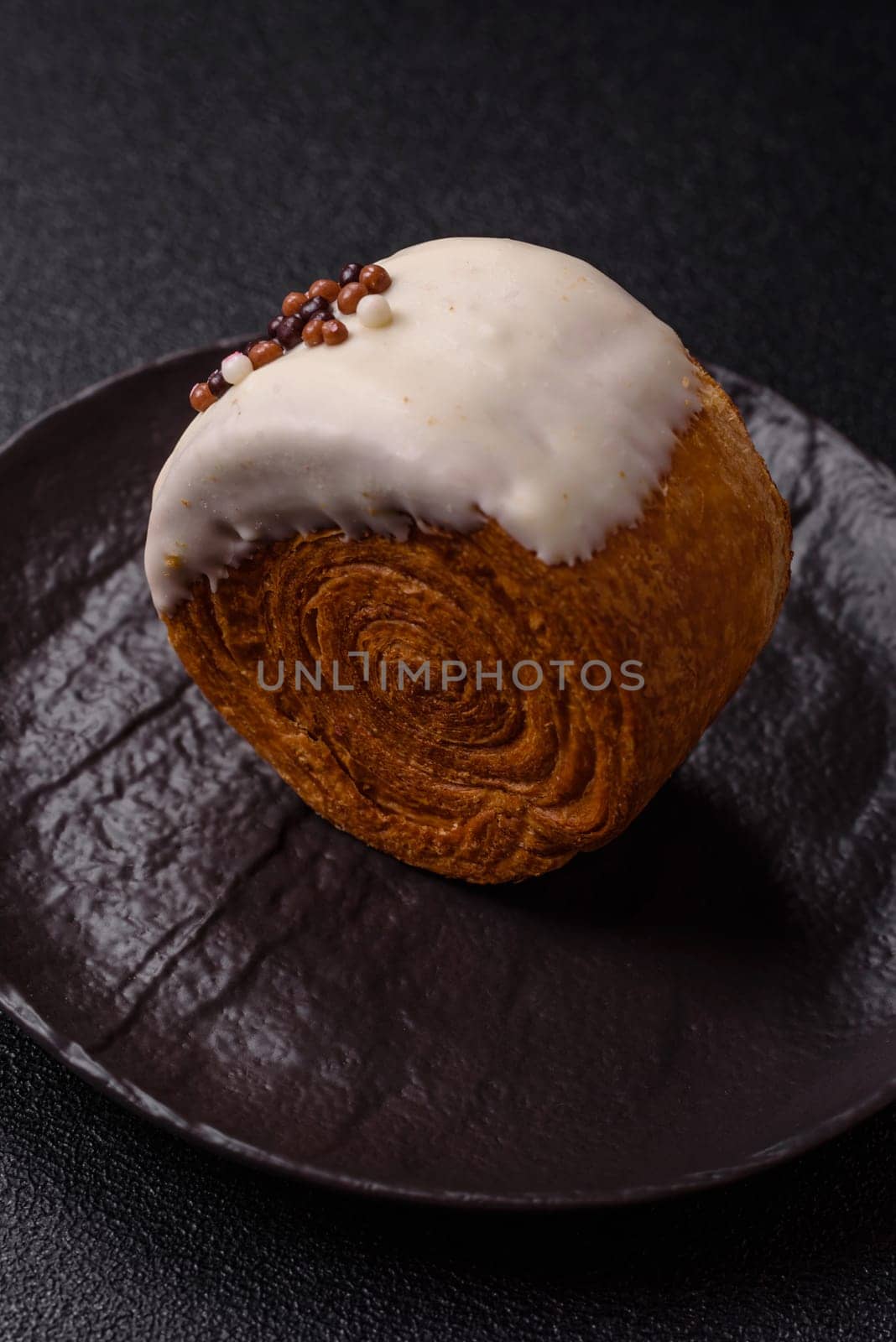 Round sweet New York roll croissant with pistachio cream filling on a dark concrete background