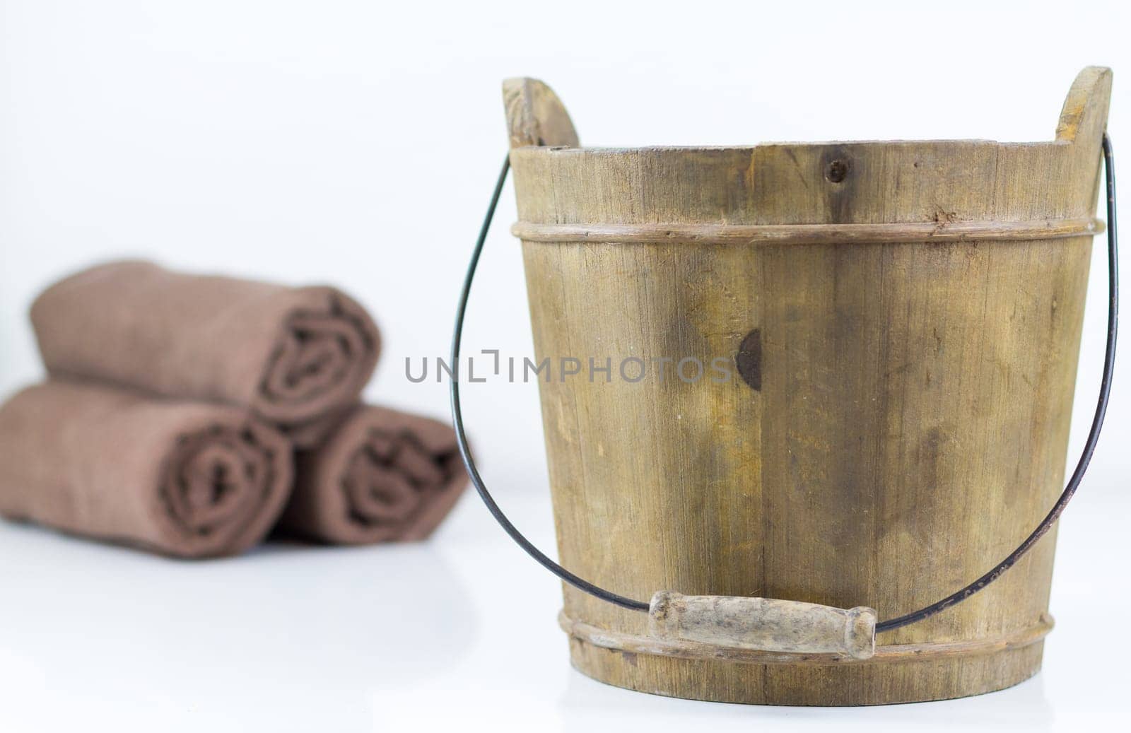A wooden bucket in close-up,towels in the background,a detail for the sauna