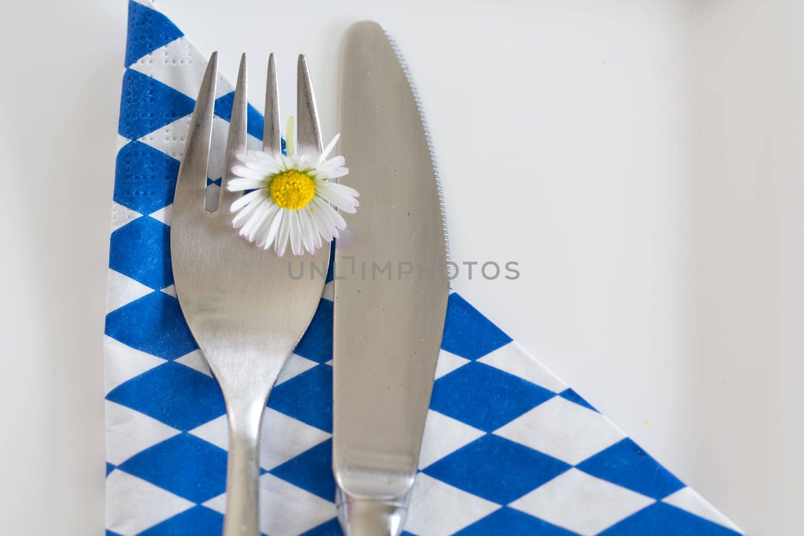 It's done - food in Bavaria! A cutlery with daisies on a white-blue napkin