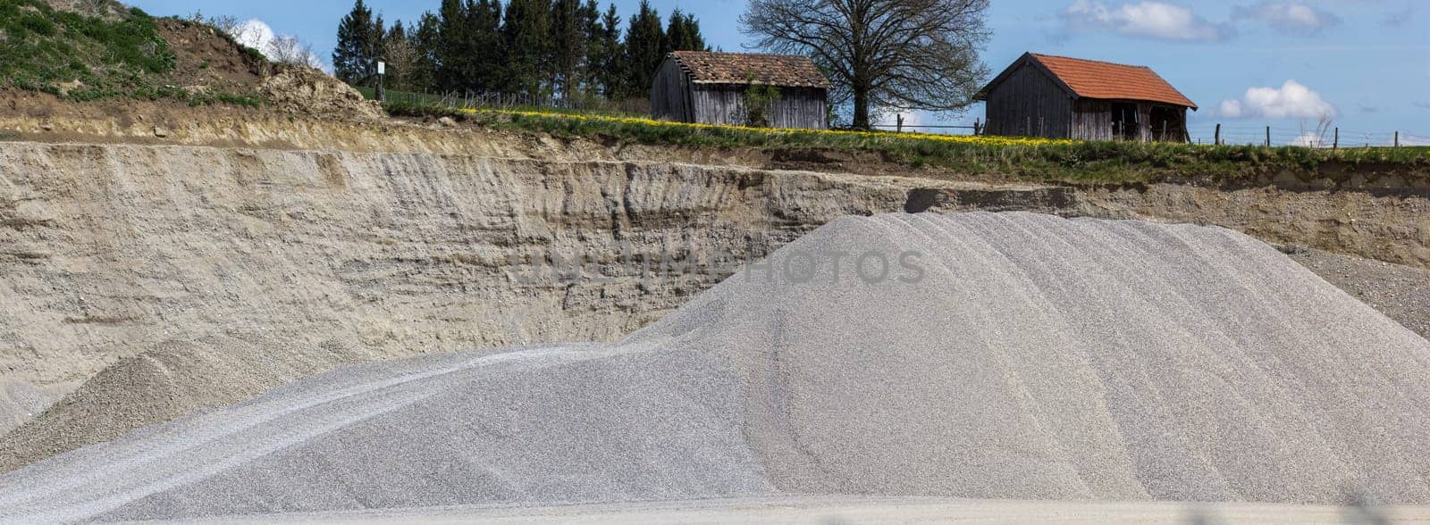 A mountain of gravel in a gravel pit - open-cast mine for road construction - a panorama