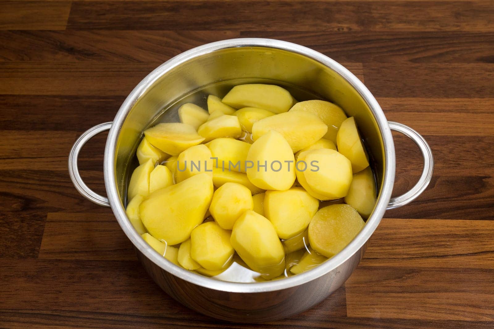 In a cooking pot,silver,freshly peeled potatoes lie in the water. So the supplement will be a pleasure!