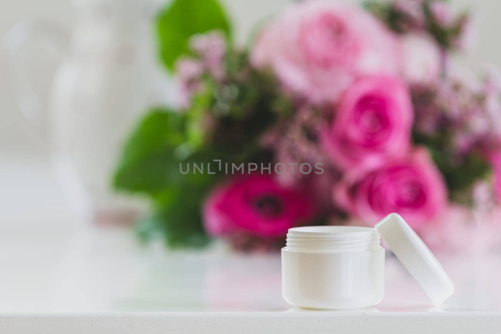 A cream can stands on the table,in the background a great bouquet of flowers that unfolds its beauty. wonderful rose tones are on the table