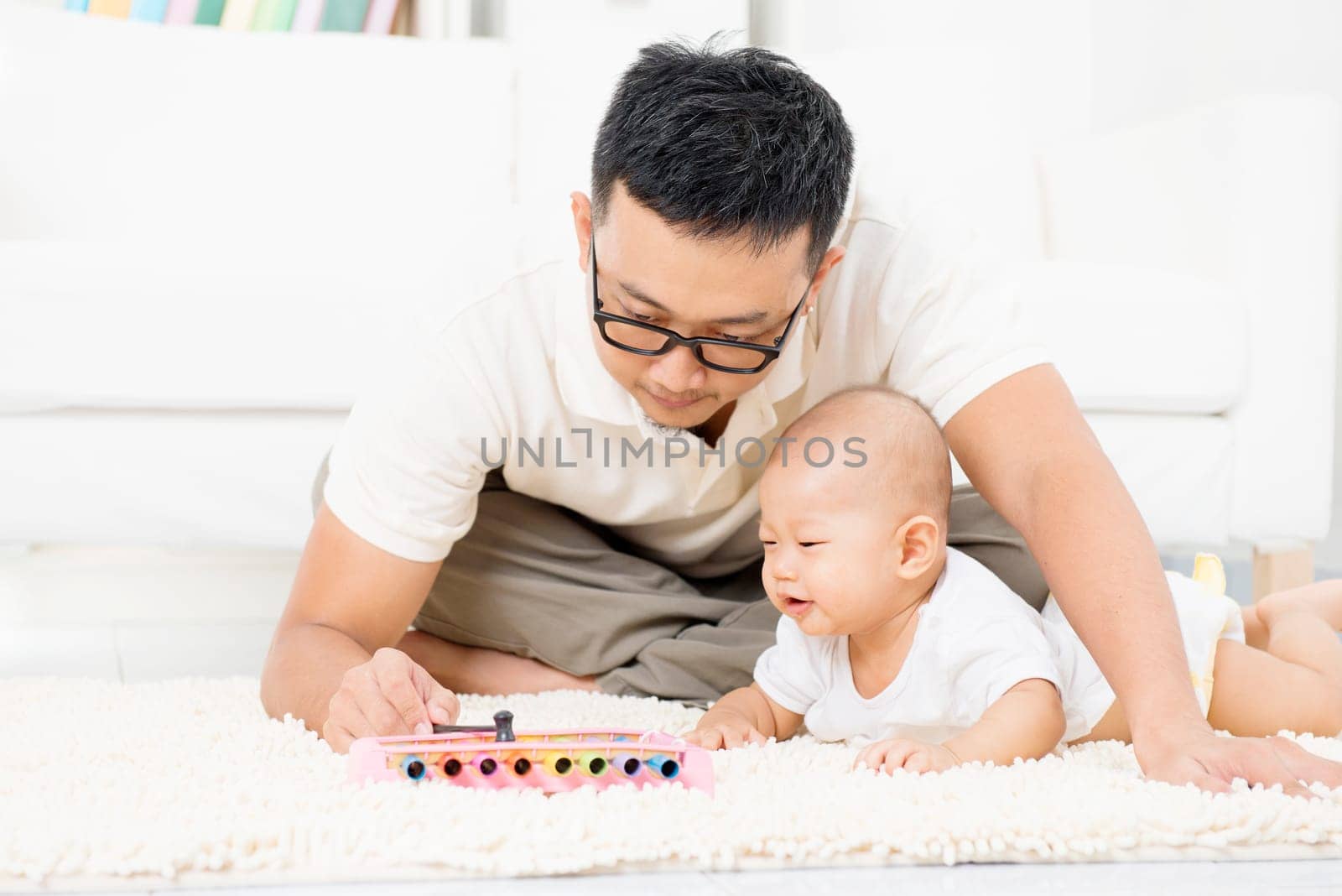 Father and baby playing music instrument. Sound development concept. Asian family lifestyle at home.
