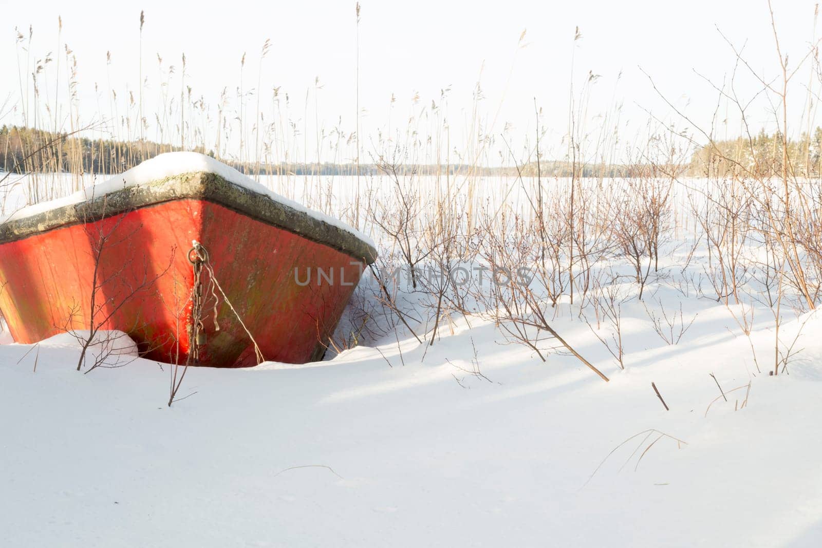 Rowboat covered in Snow by lake.