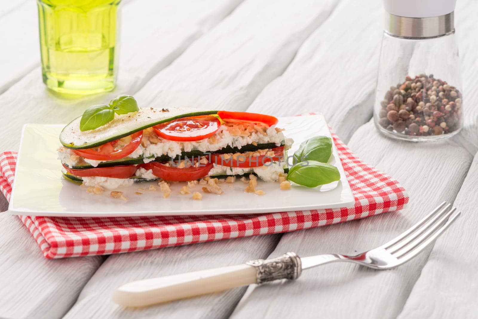 Delicious Italian appetizer of tomato, zucchini slices, nuts, basil and fresh cheese.