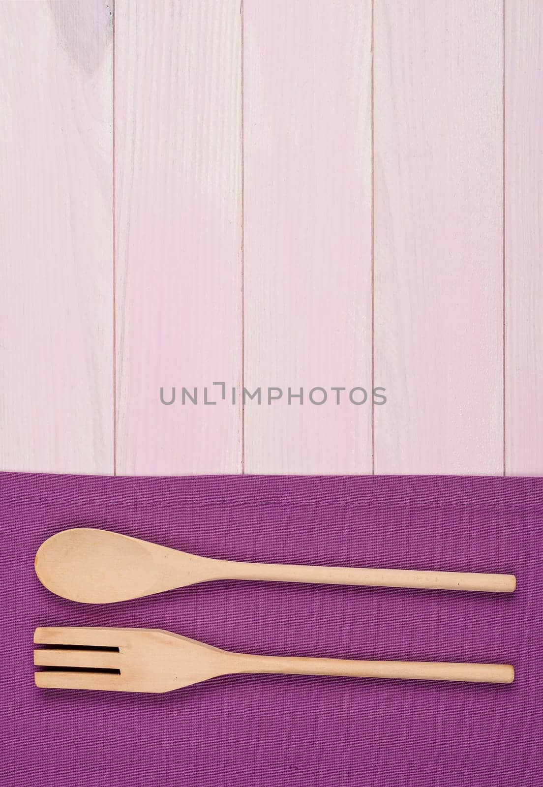 Kitchenware on purple towel over wooden kitchen table. View from above.