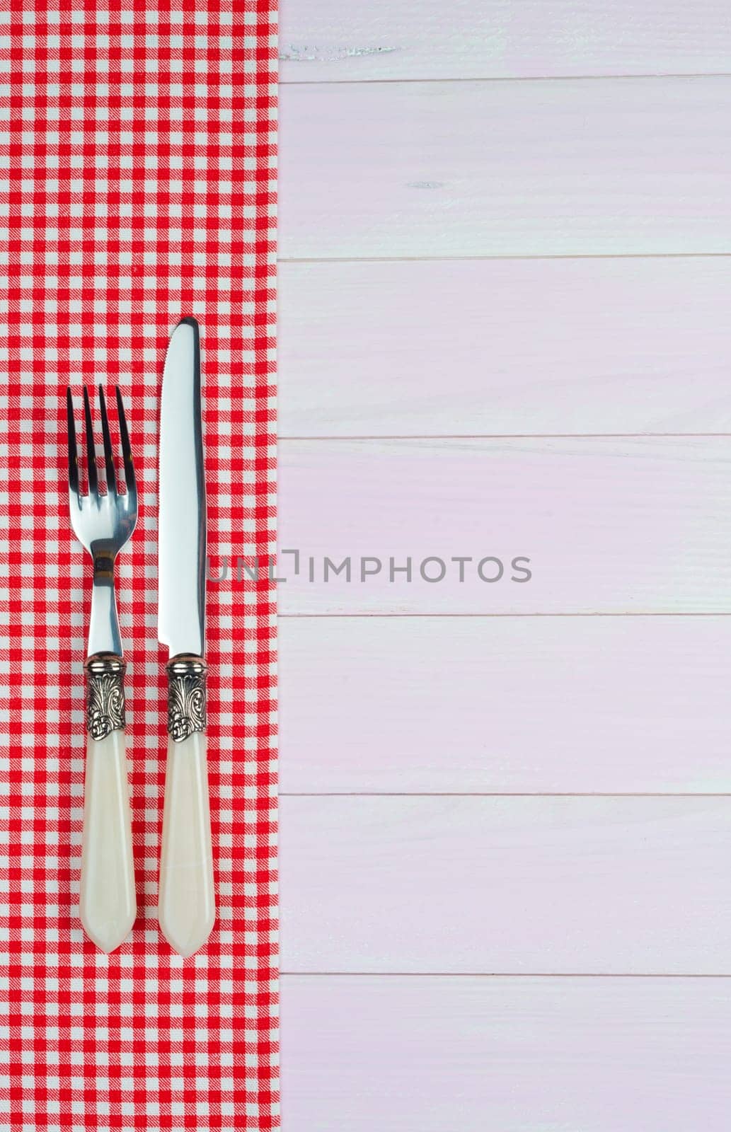 Kitchenware on white and red towel over wooden kitchen table. View from above.