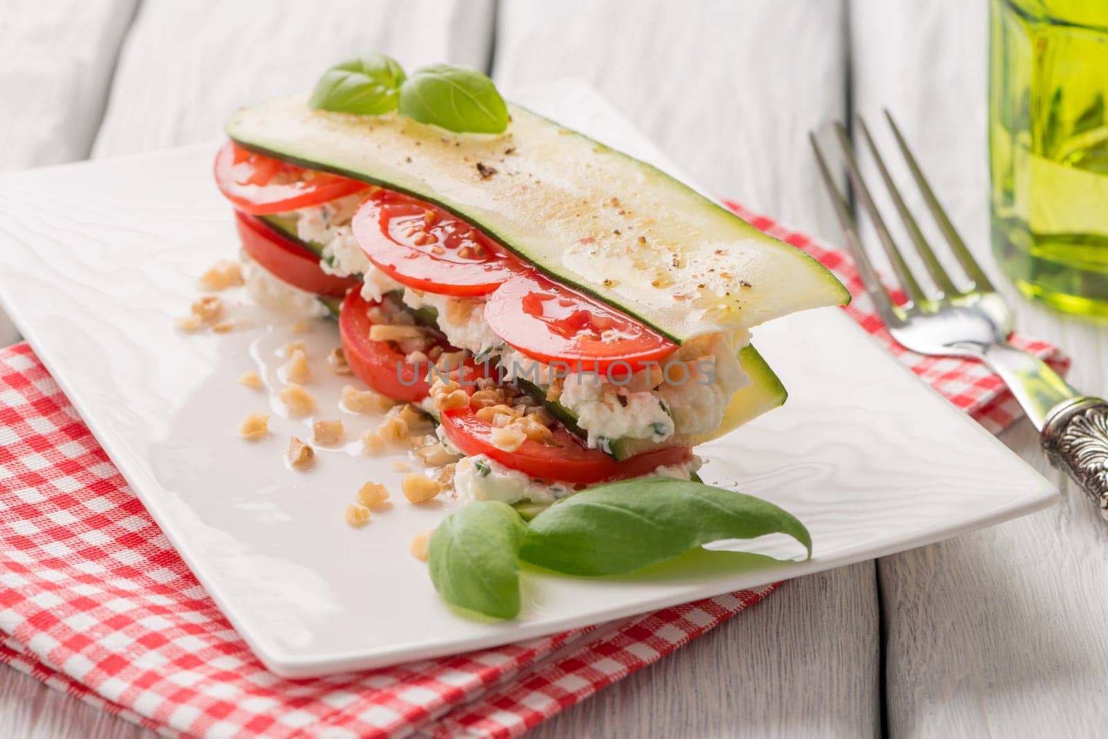 Delicious Italian appetizer of tomato, zucchini slices, nuts, basil and fresh cheese.