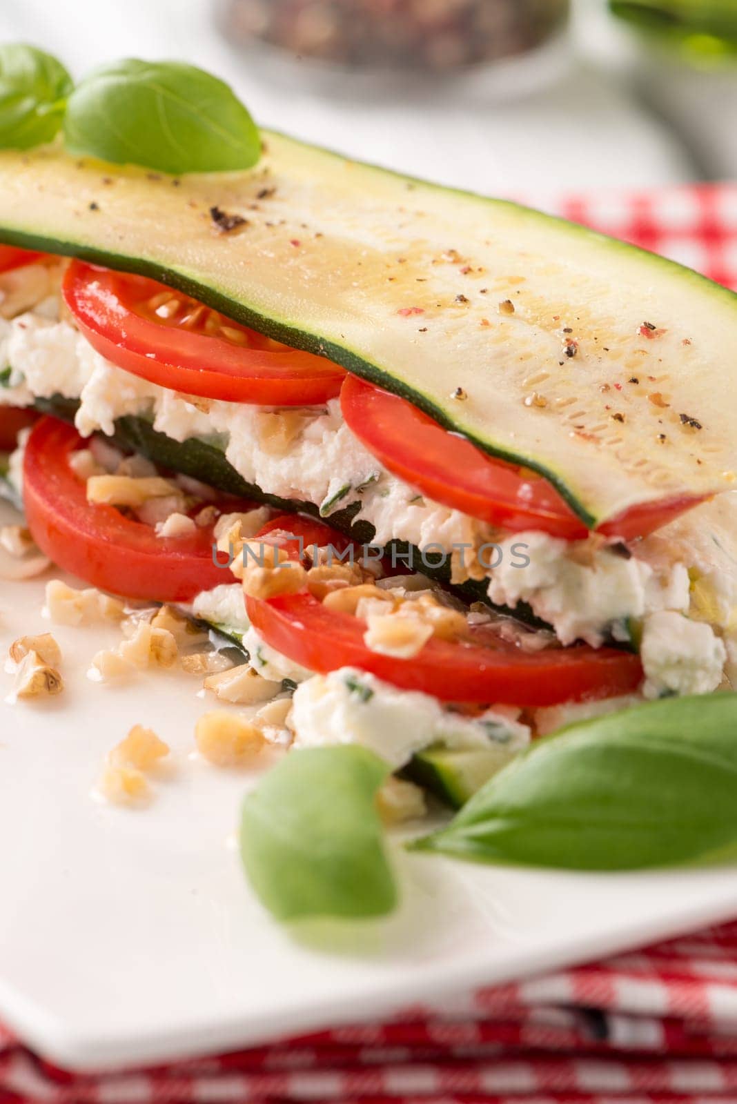 Delicious Italian appetizer of tomato, zucchini slices, nuts, basil and fresh cheese.