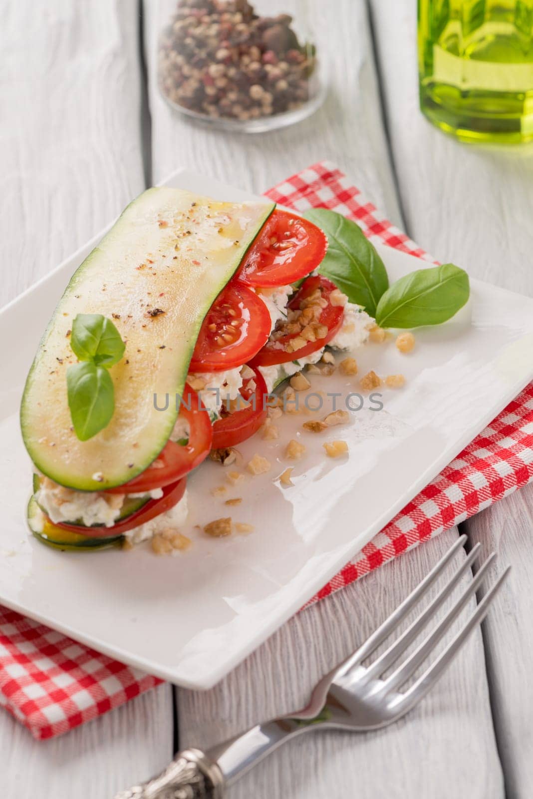 Delicious Italian appetizer of tomato, zucchini slices, nuts, basil and fresh cheese.