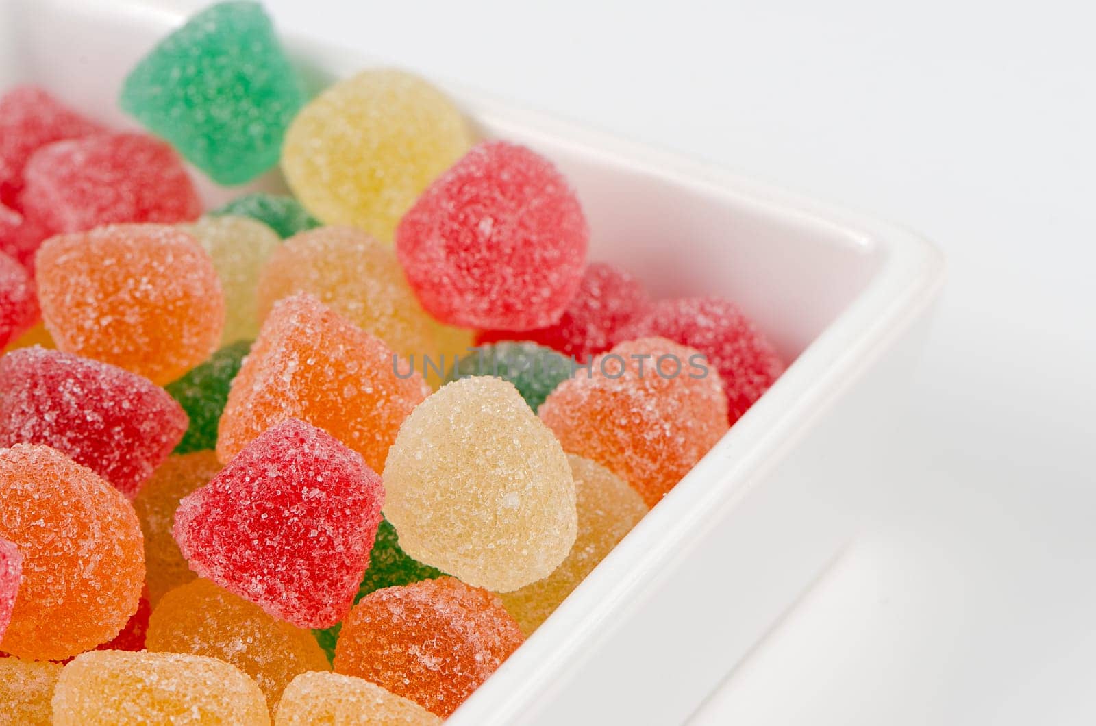Jelly sugar candies in a white ceramic containter on white background.