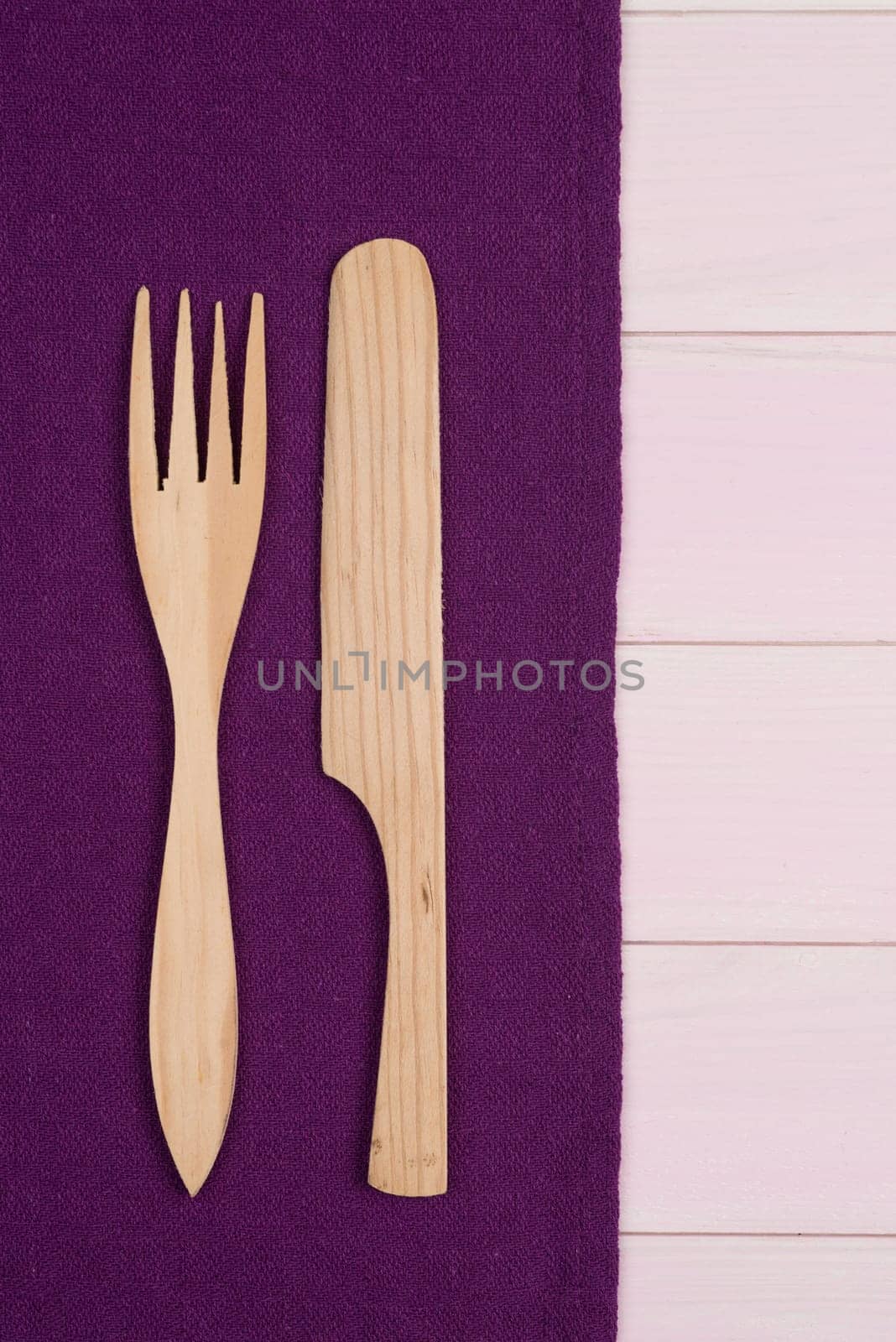 Kitchenware on purple towel over wooden kitchen table. View from above.