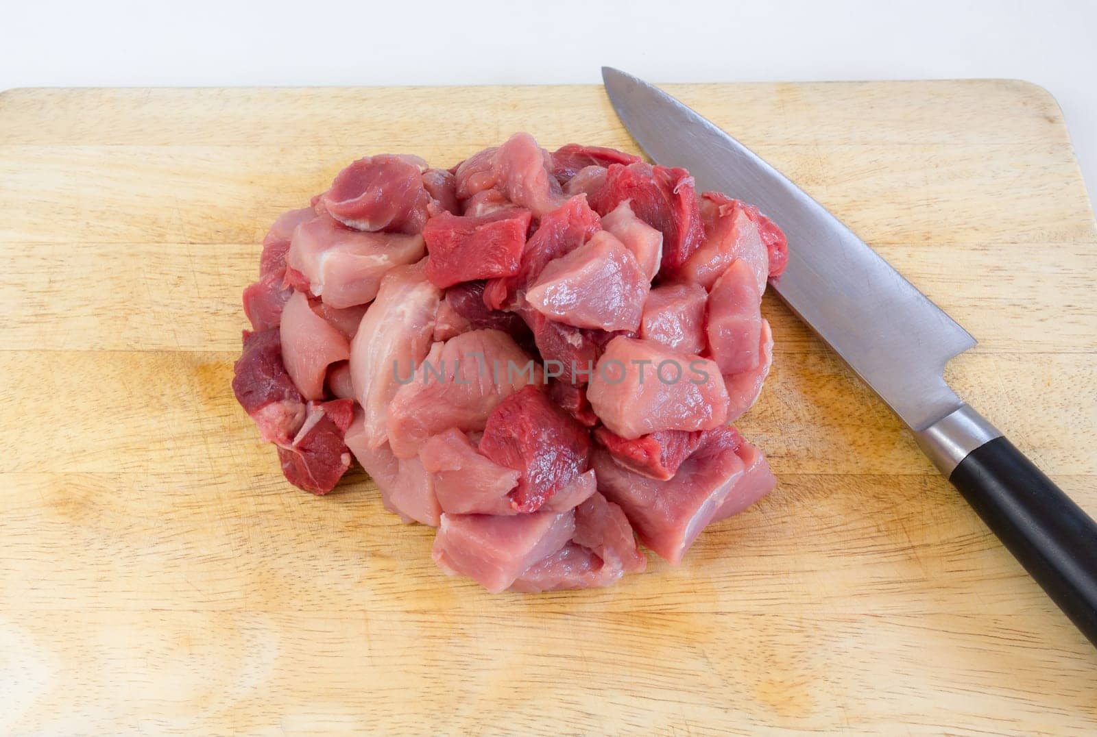 Goulash - on a wooden board lies next to a large knife,raw,cut meat