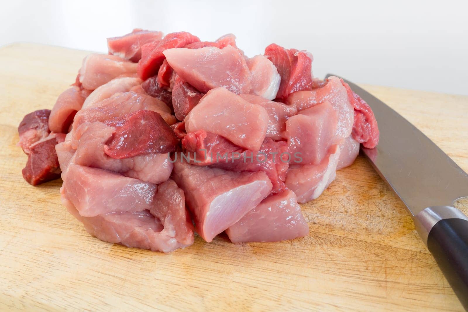 Goulash - on a wooden board lies next to a large knife,raw,cut meat