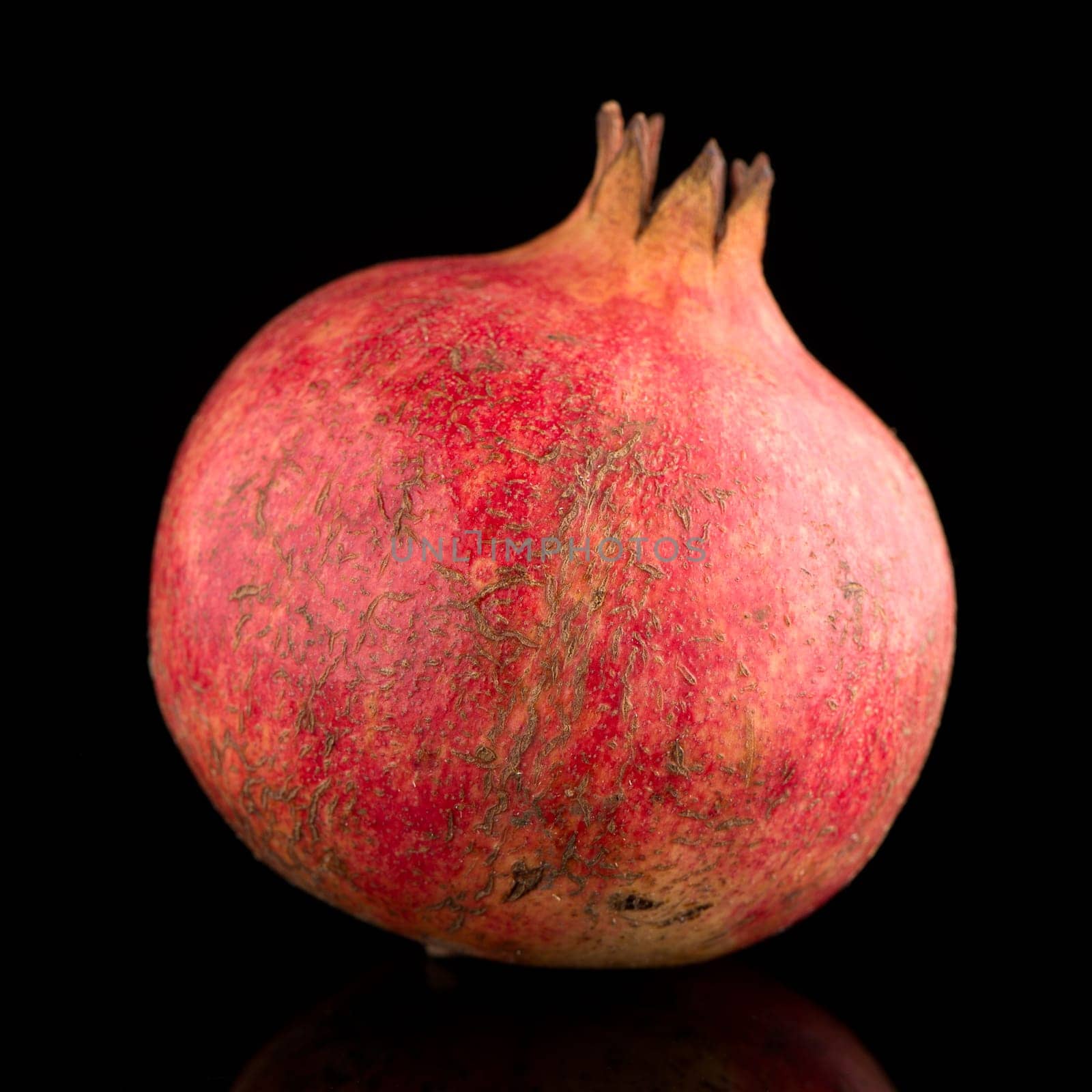 Ripe pomegranate fruit with leaves on black background
