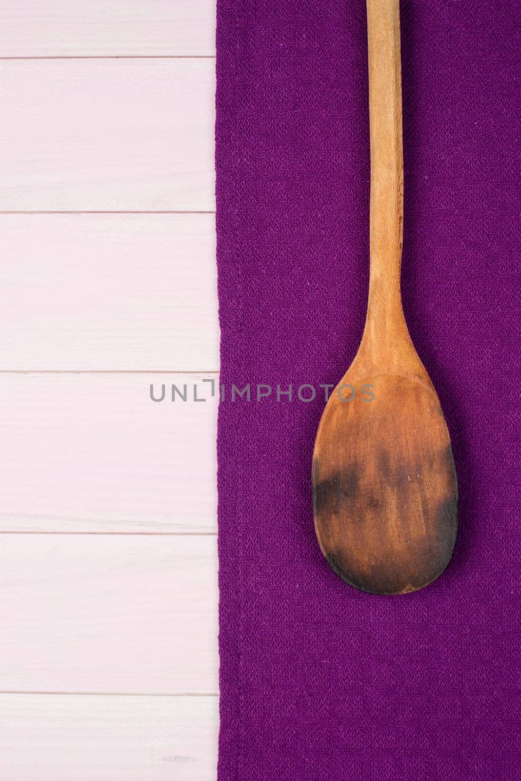 Kitchenware on purple towel over wooden kitchen table. View from above.
