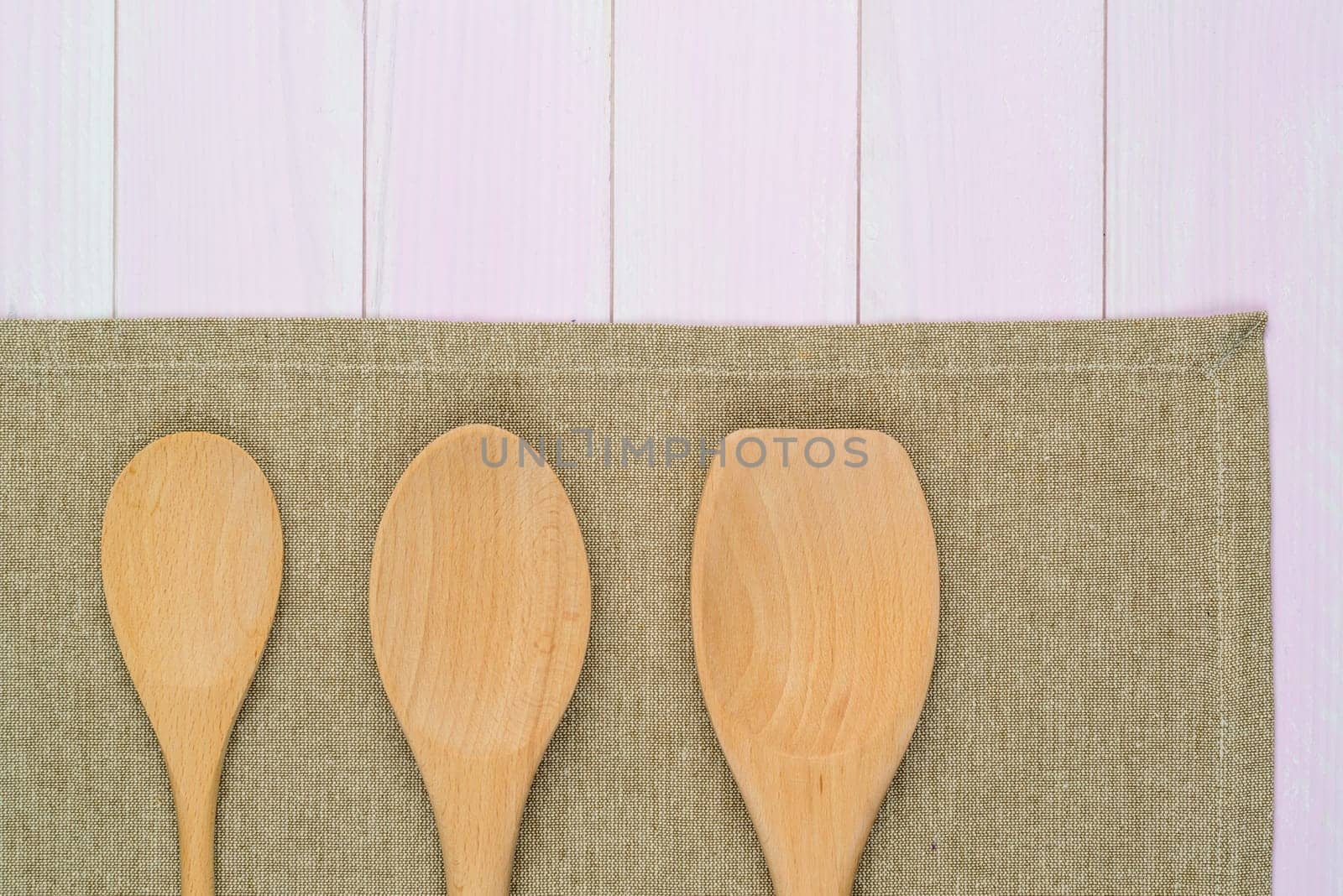 Kitchenware on beige towel over wooden kitchen table. View from above.