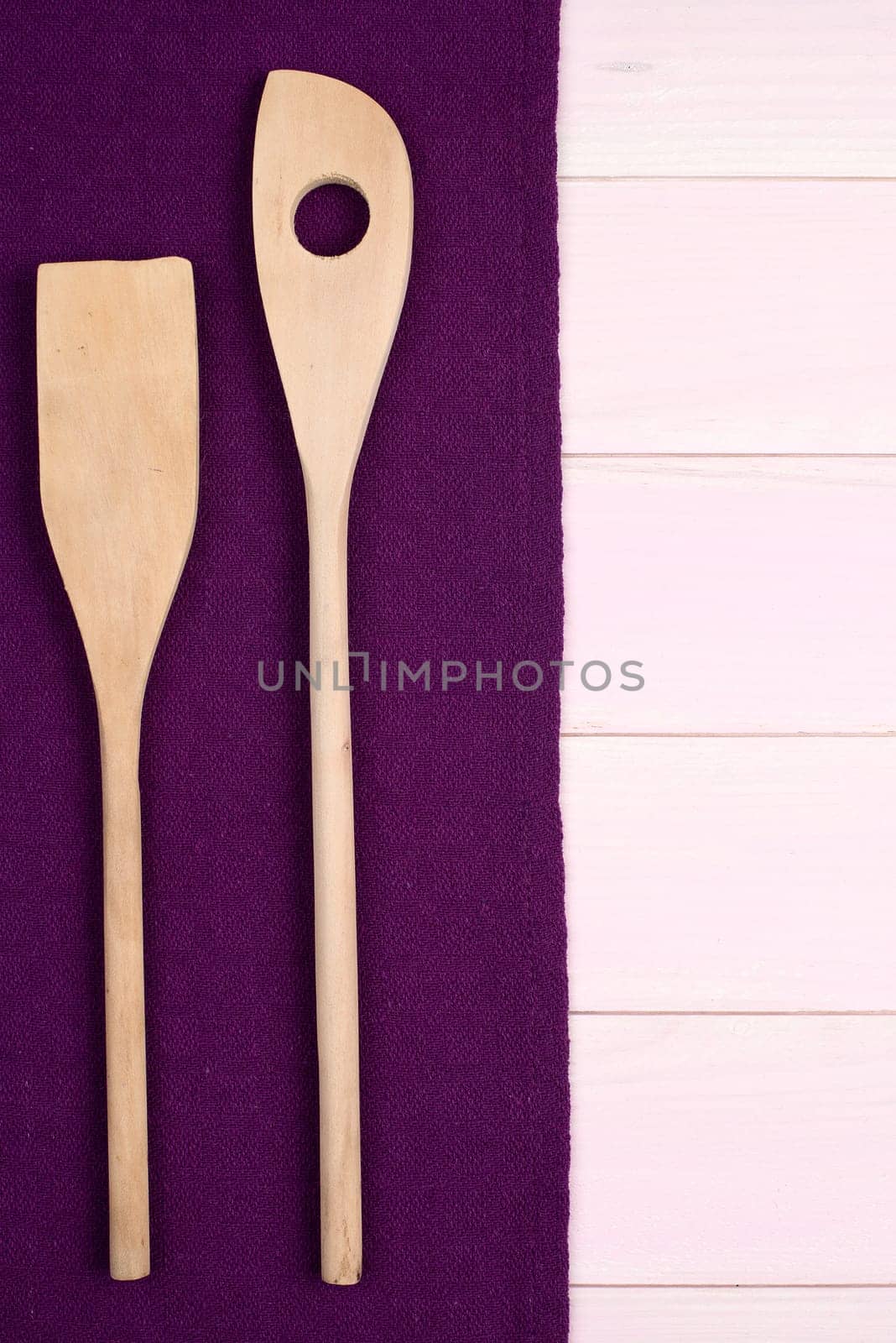 Kitchenware on purple towel over wooden kitchen table. View from above.