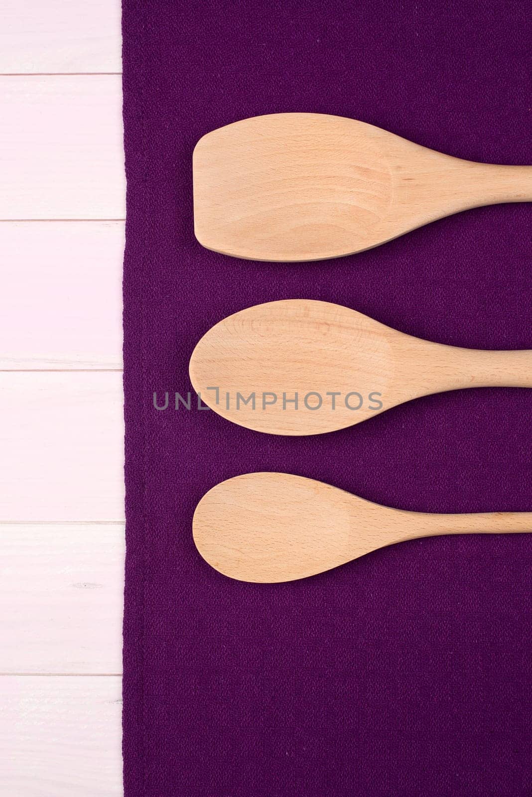 Kitchenware on purple towel over wooden kitchen table. View from above.