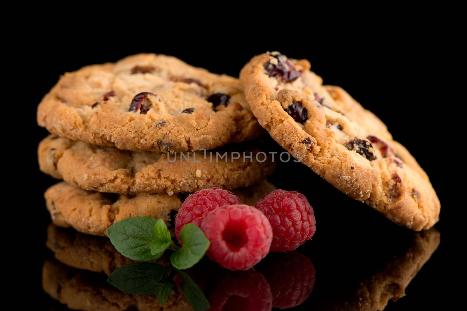 Dried fruits chip cookies and raspberries isolated on black background.