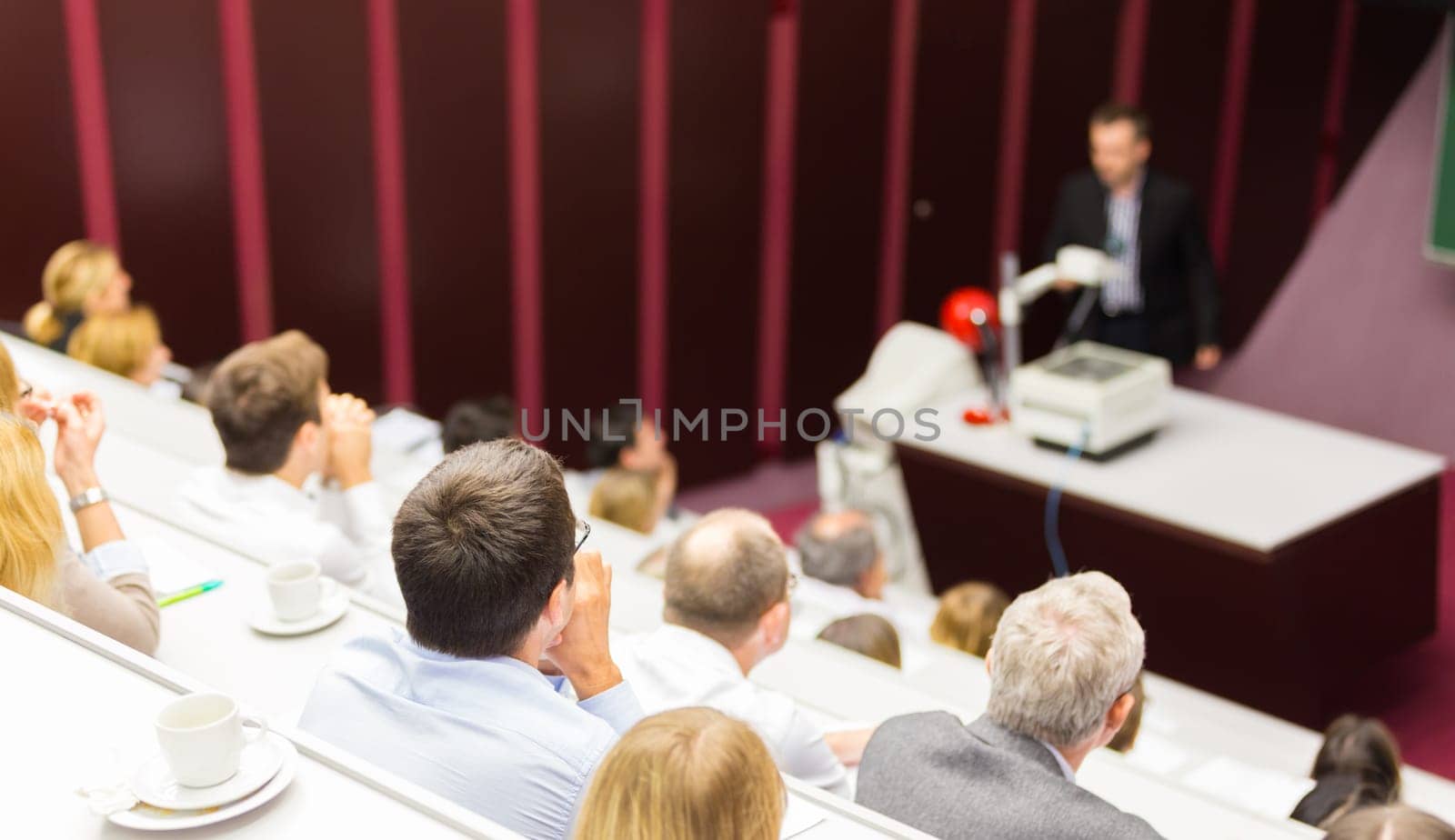 Lecturer at university. Medical expert giving a talk as an faculty professor. Participants listening to lecture and making notes.