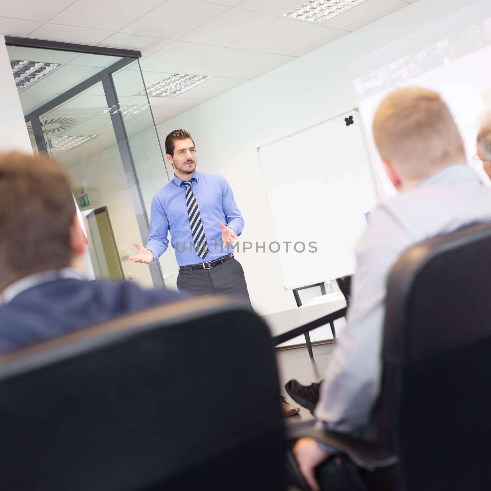 Business man making a presentation at office. Business executive delivering a presentation to his colleagues during meeting or in-house business training, explaining business plans to his employees.
