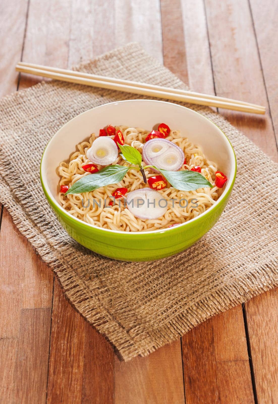 Noodle in bowl with chopsticks on wooden background