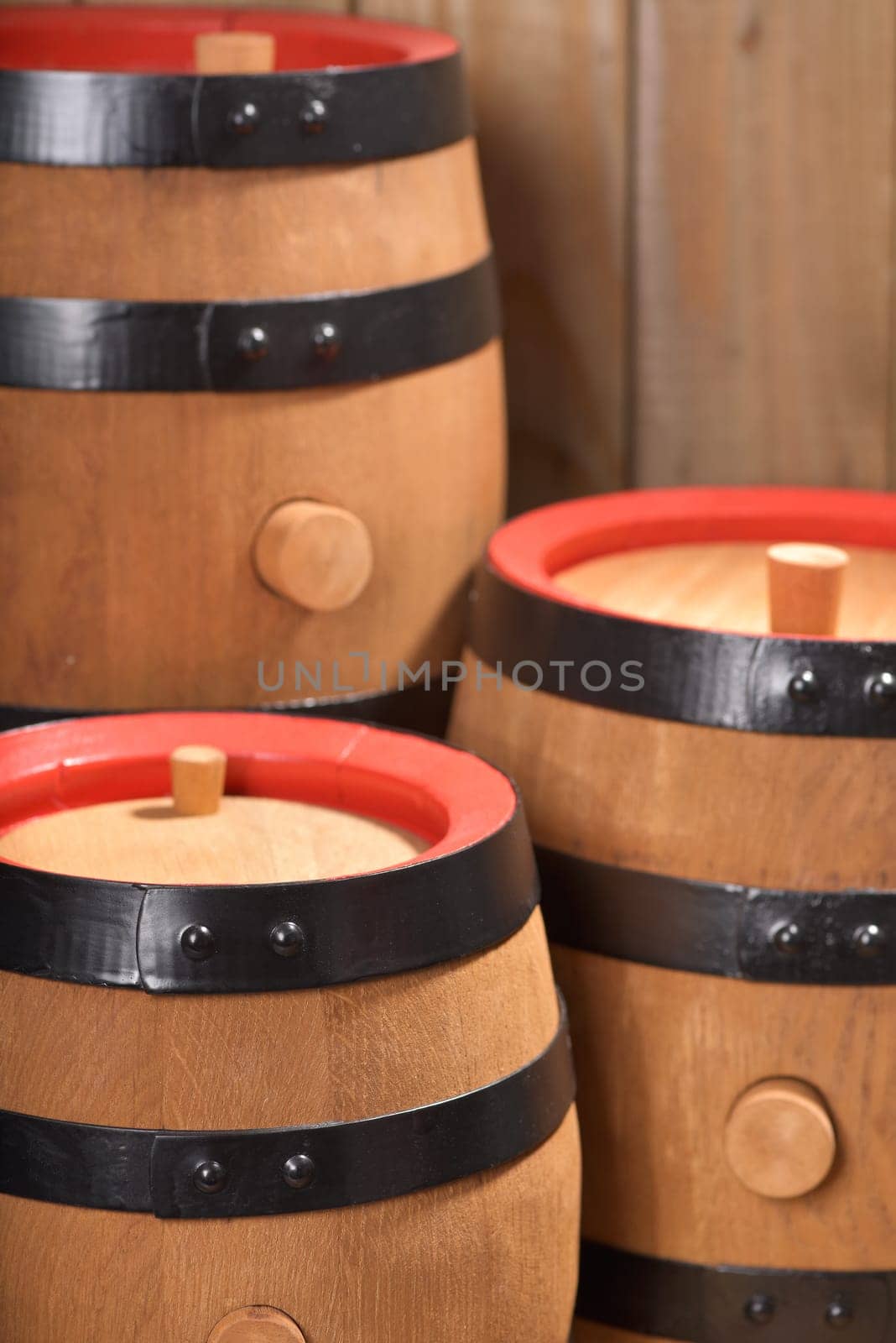 three old beer barrels with wooden plugs on a wooden background