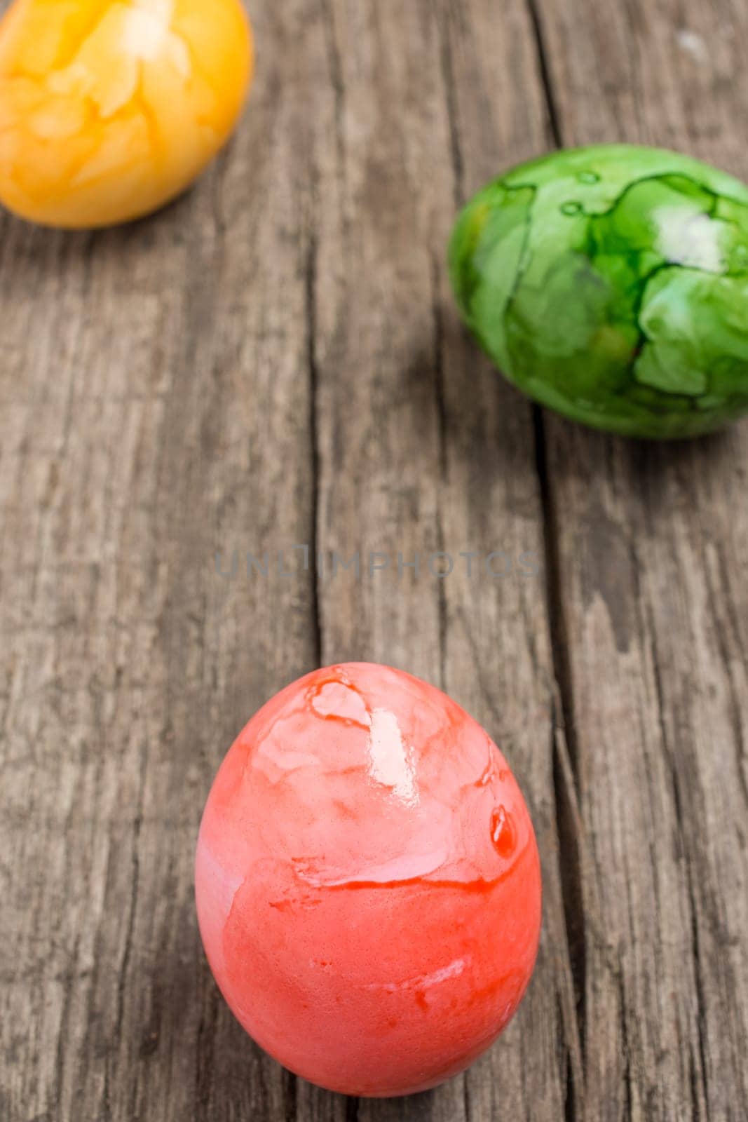 Painted coloured Easter eggs on old wood in portrait format