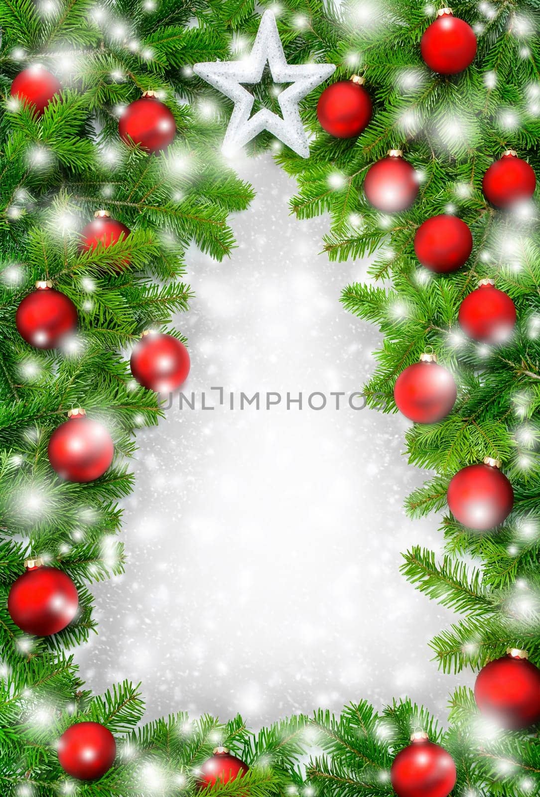 A frame of fir branches,Christmas baubles and snow forms the outline of a Christmas tree