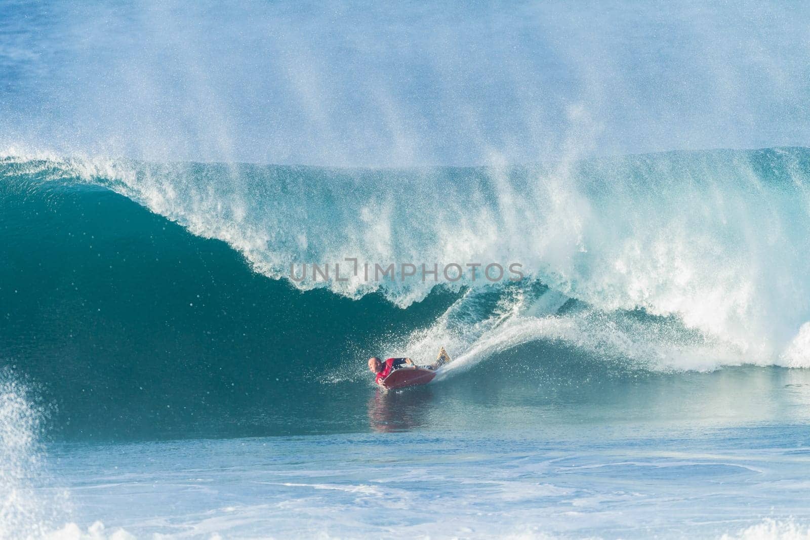 Surfing body-boarder rides large ocean wave