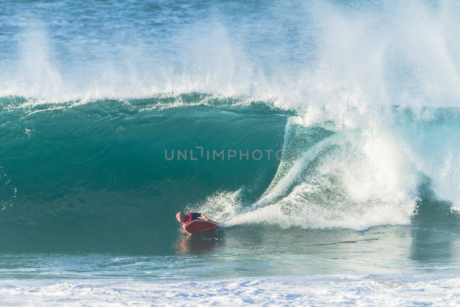 Surfing body-boarder rides large ocean wave