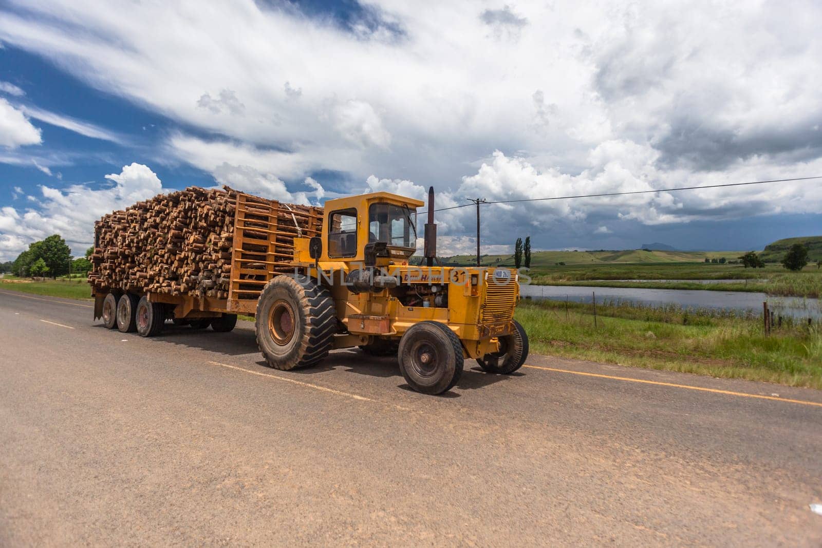 Tractor trailer with cut tree logs in mountain countryside to wood mill.