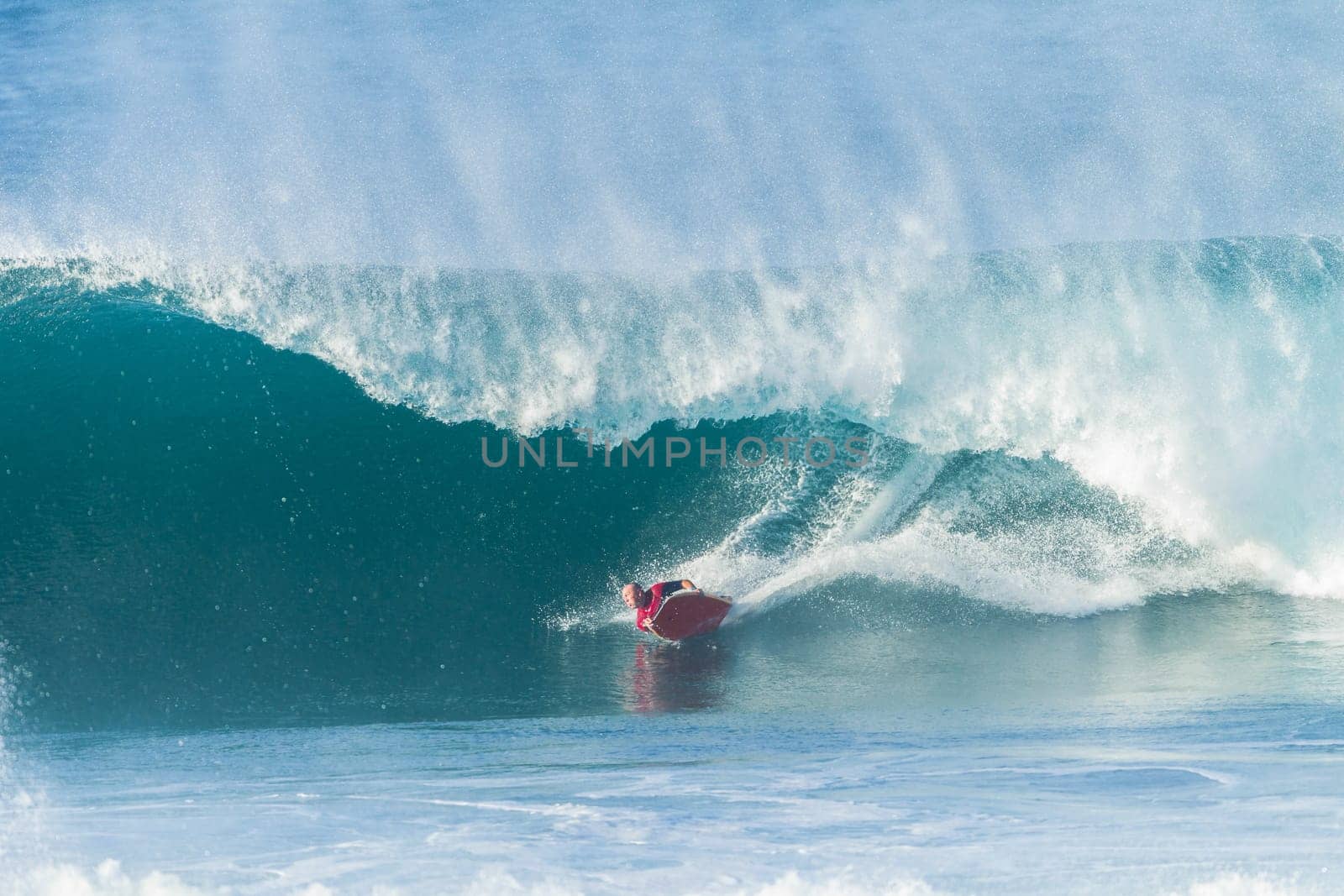 Surfing body-boarder rides large ocean wave