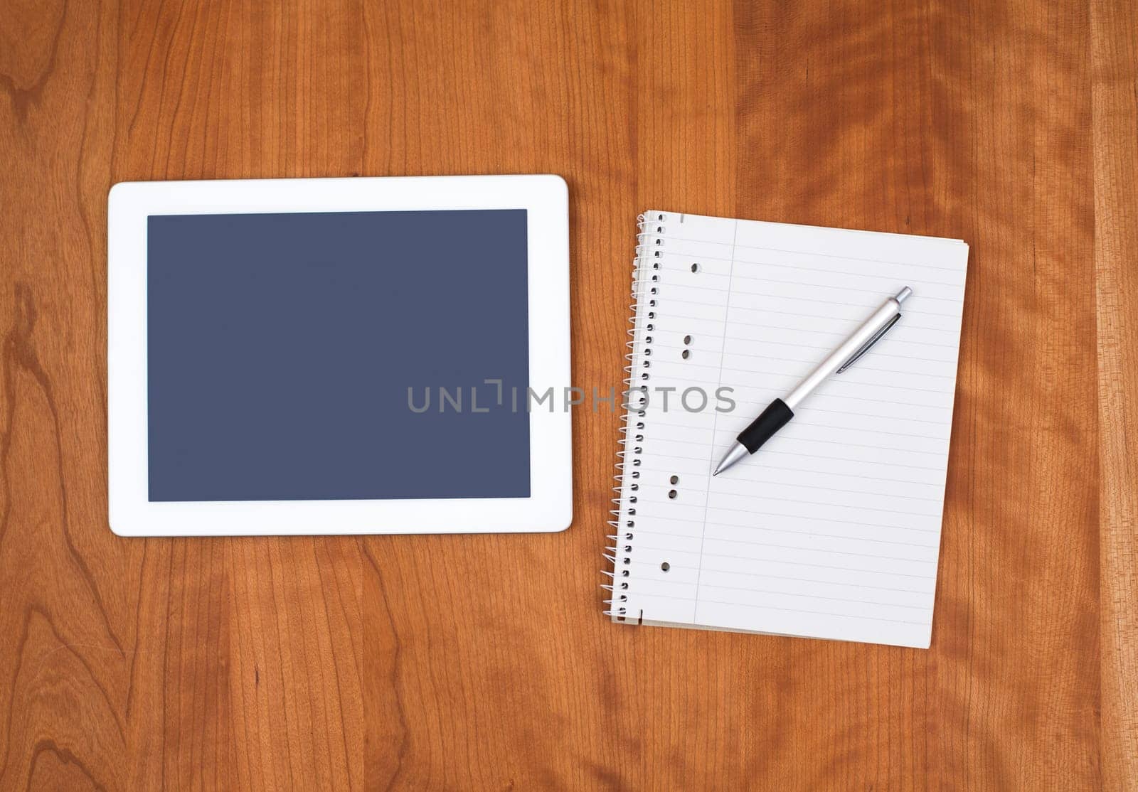 tablet PC and notepad with pen on wooden table from above